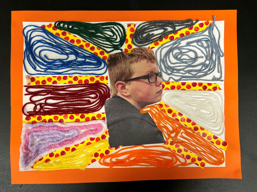 A multicolored yarn-based ray artwork with a boy's picture in the middle. 